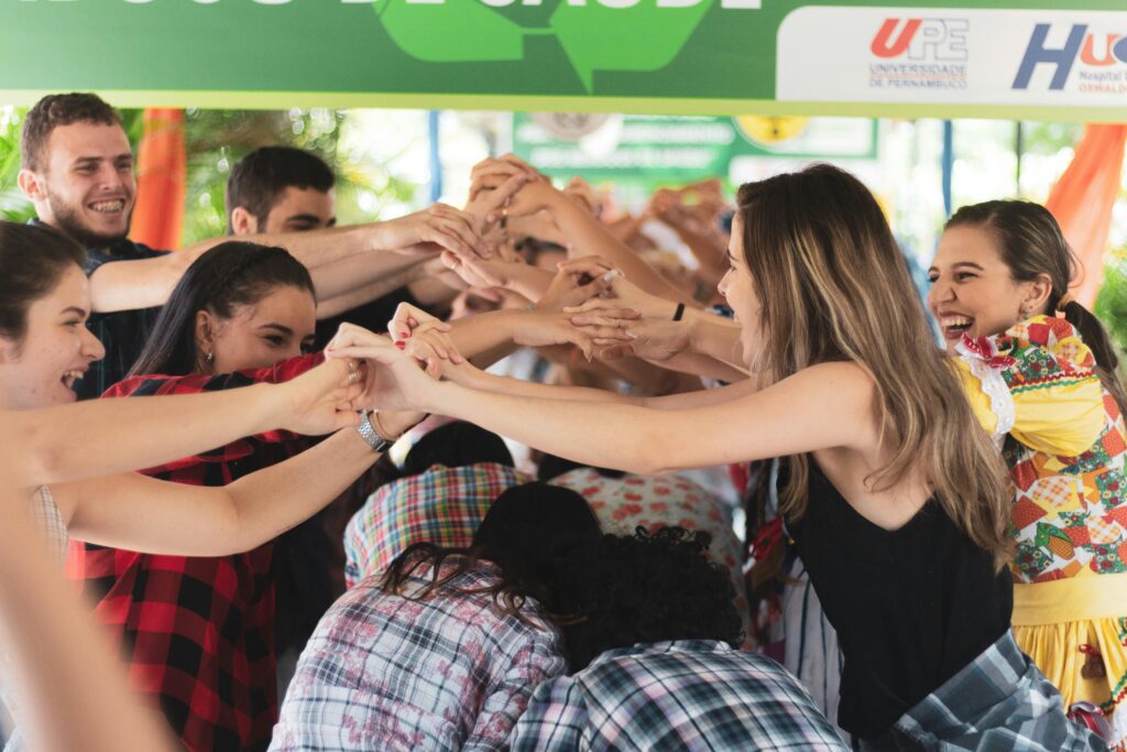 Group of diverse students engaging in a fun hand-holding activity indoors, symbolizing friendship and togetherness.